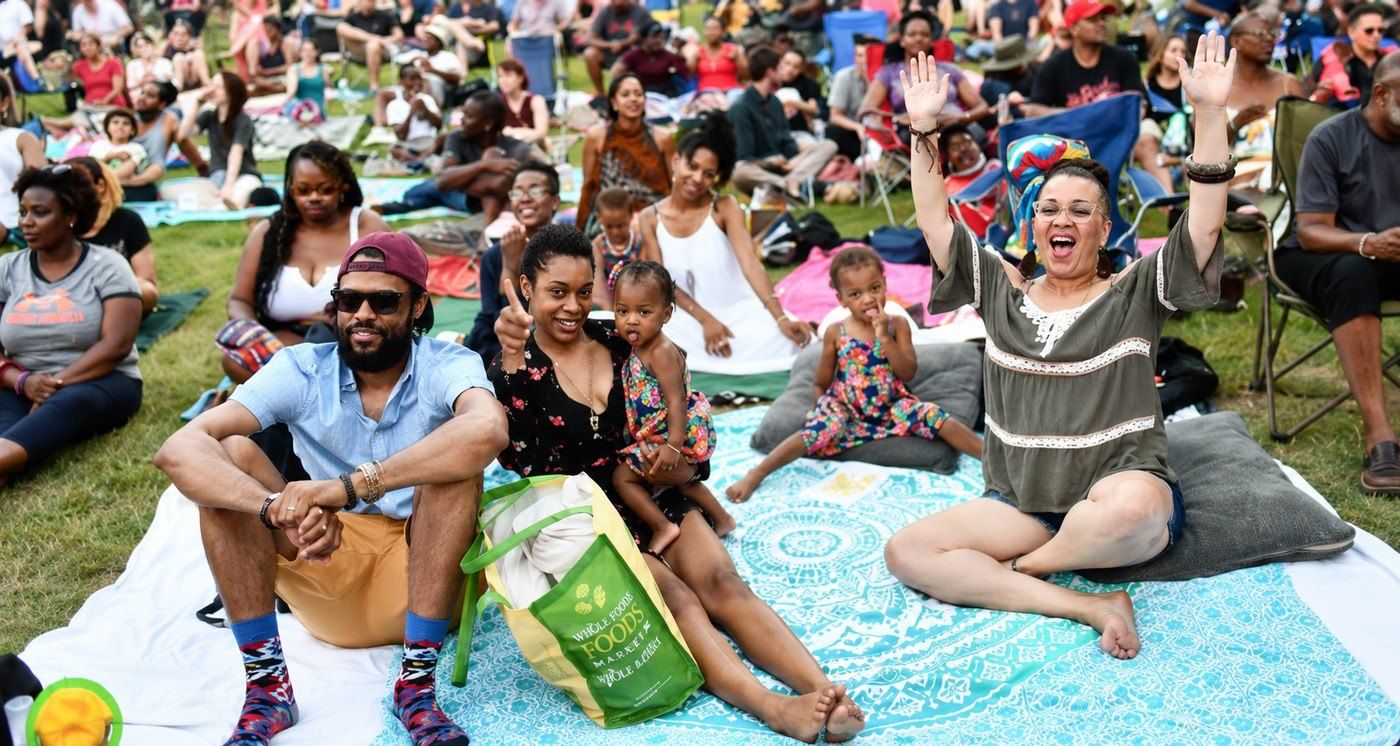 Friends and family on a picnic blanket enjoying a free outdoor concert